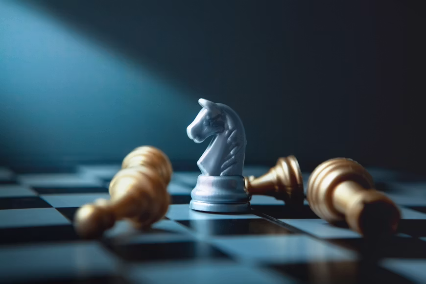 Une pièce d’échecs blanche reste debout face à deux pièces tombées, symbole d’avantage compétitif