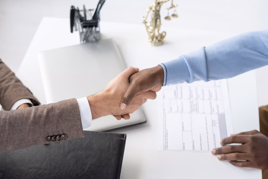 Deux professionnels se serrent la main au-dessus d’un plan, symbole d’un accord fournisseur